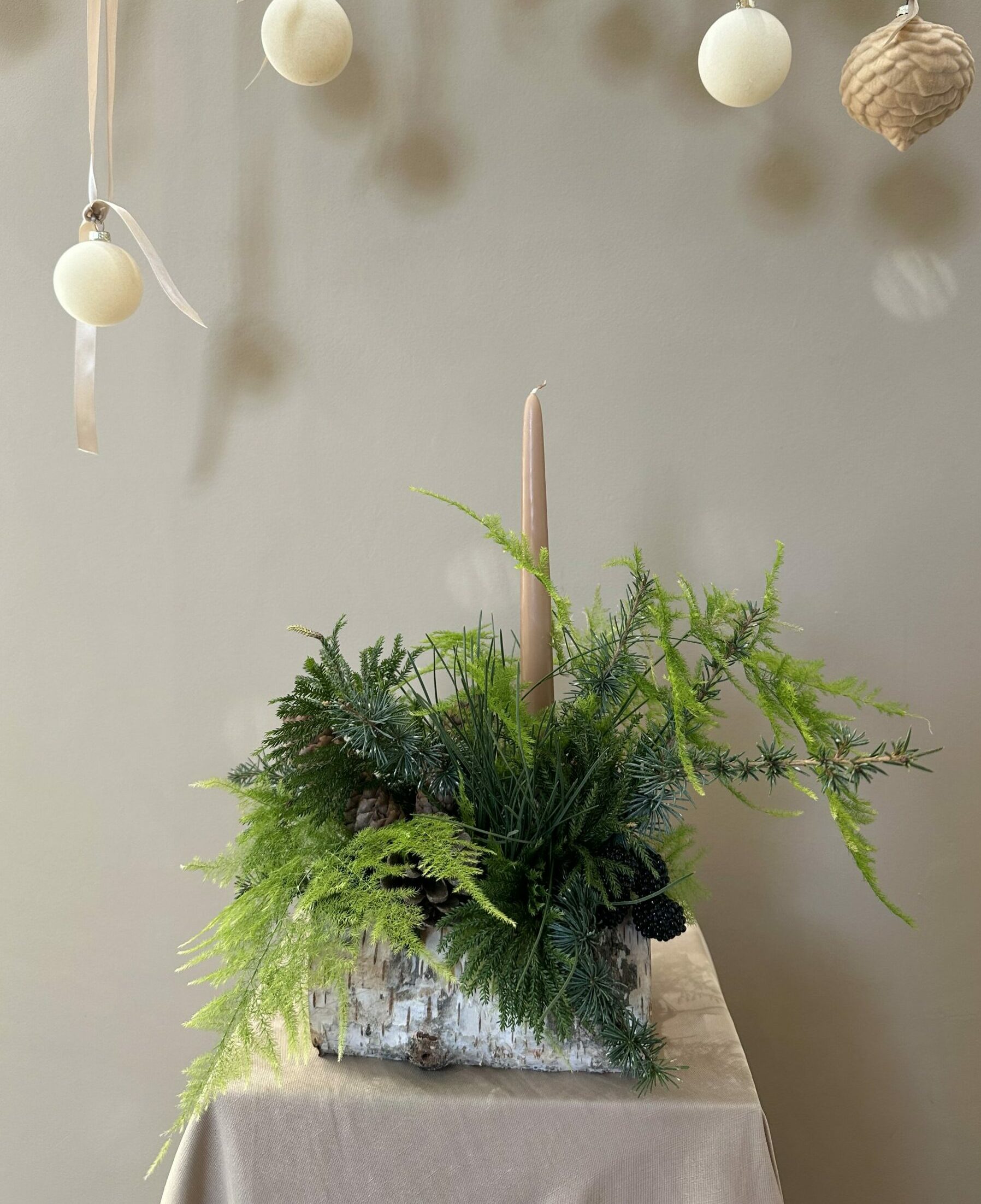 Bûche végétale La Naturelle, feuillages clairs, mousse douce et accessoires minimalistes monochromes, composition épurée Parenthèse Florale Lyon.